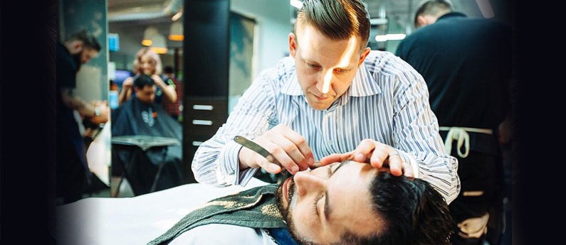 Barbering student giving a client a nice, close shave.