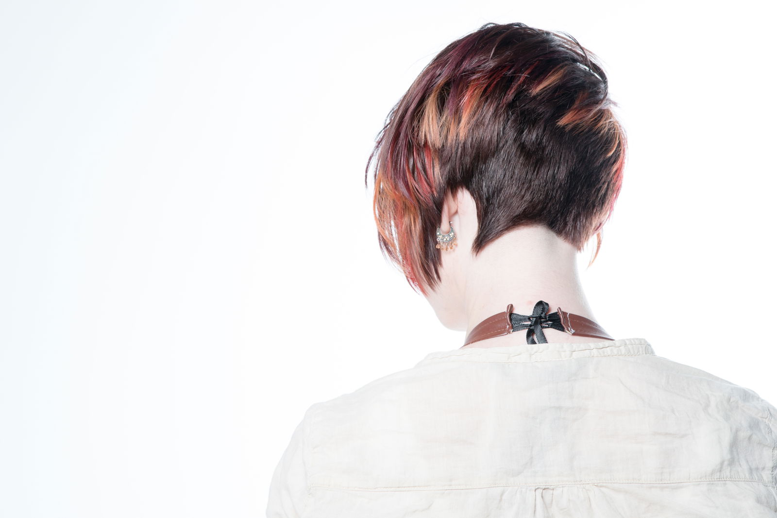 Model with a pixie cut that has orange highlights at the ends, view from the back