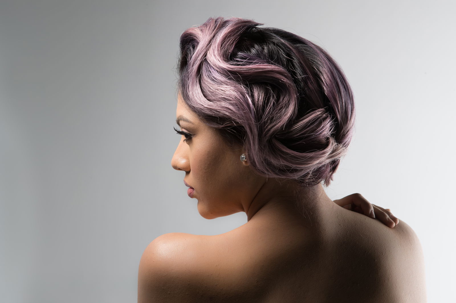 Model with pastel-lilac hair that is swept up in a wavy updo from another angle