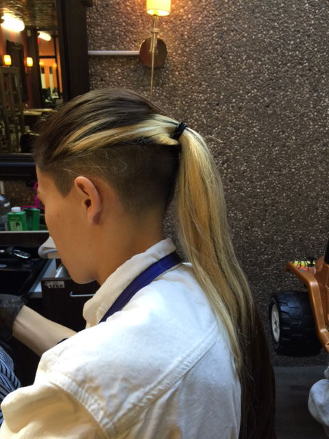 Bleached long hair pulled back, showing an undercut.