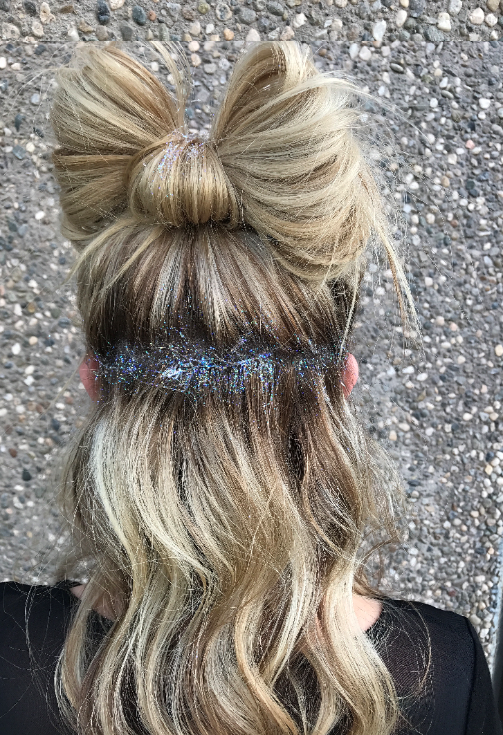 Cute updo with hair in the shape of a bow and covered in glitter.